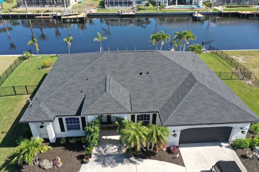 Small Florida home with a brand new rust colored shingled roof installed by 1st Alert Roofing Florida